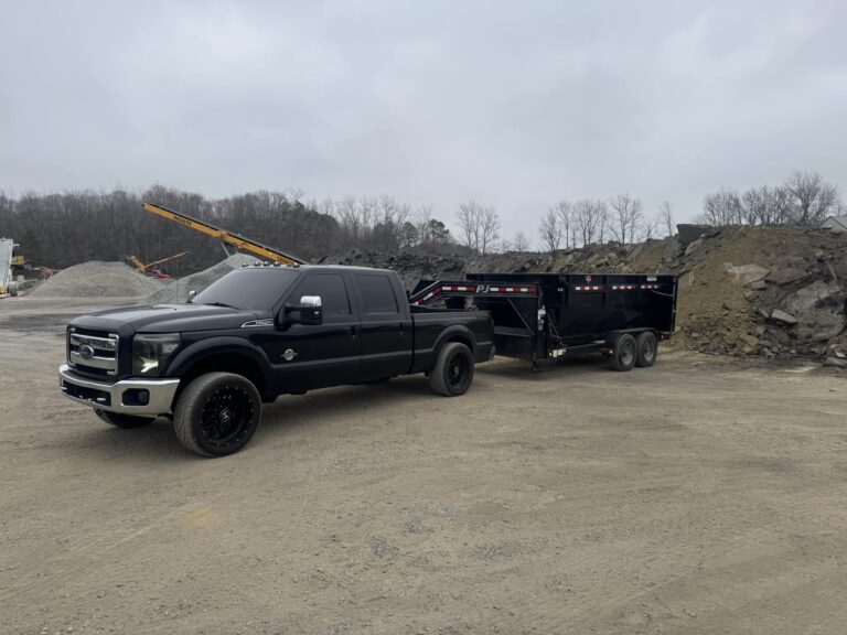Black pickup truck towing a dumpster in a construction site, showcasing waste management solutions for homeowners and contractors.